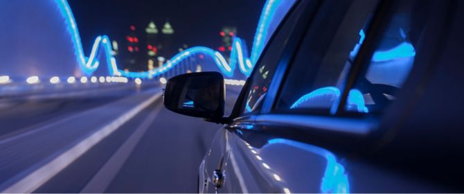 Rear view mirror of car on illuminate bridge
