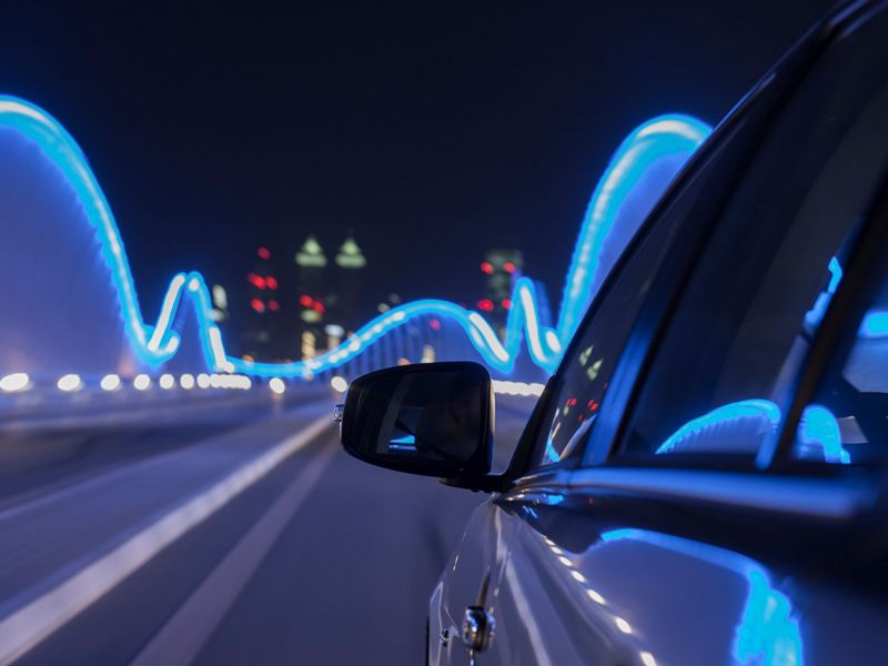 Rear view mirror of car on an illuminated bridge