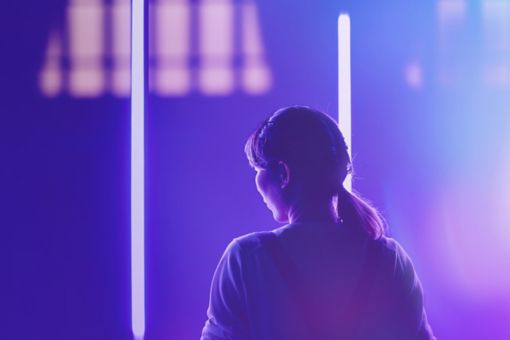 Rear view of woman standing against illuminated lights at night