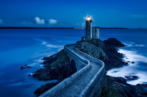 Lighthouse on the sea in the night across bridge