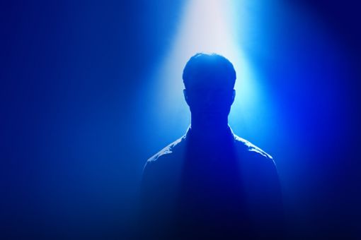 Silhouette of man standing under spotlight