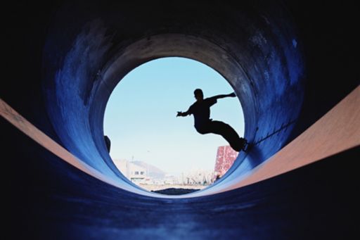 Silhouette of man skateboarding in tunnel