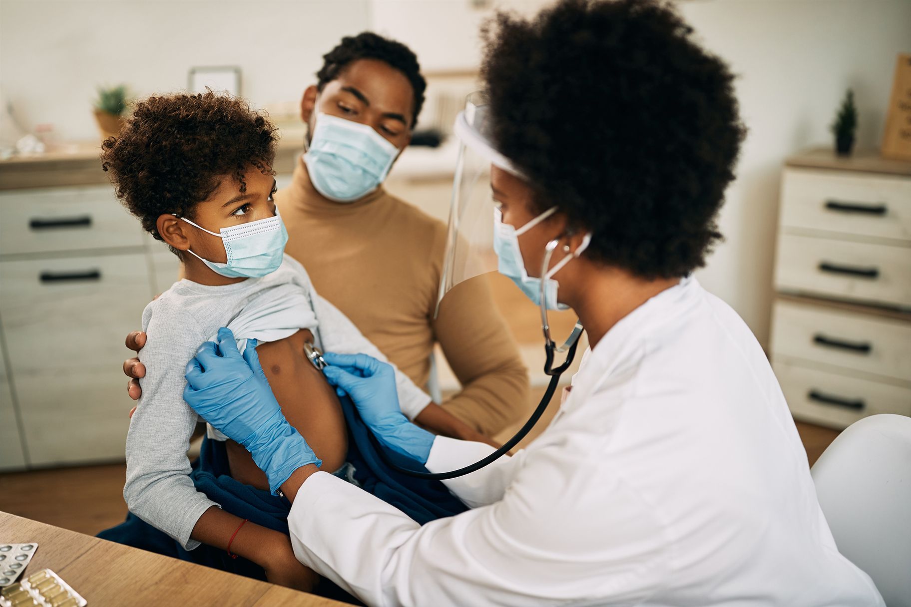 Small black boy having medical exam at doctor's office during coronavirus pandemic.