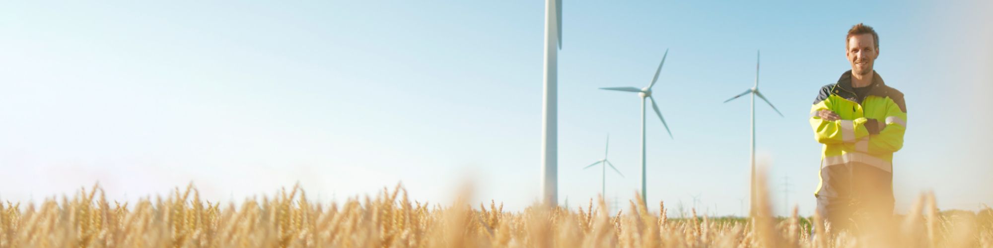 Smiling engineer standing in a field at a wind farm