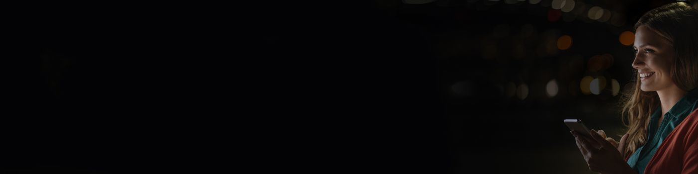 Smiling girl using phone with dark background