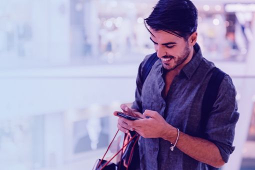 Smiling man texting in the shopping centre