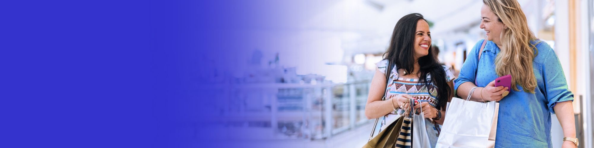 Two happy women holding shopping bags in a retail shopping centre