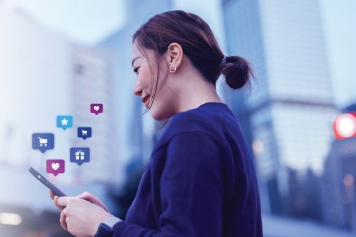 Smiling young Asian woman using smartphone to shop online