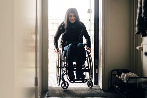 Social housing woman in wheelchair coming through front door
