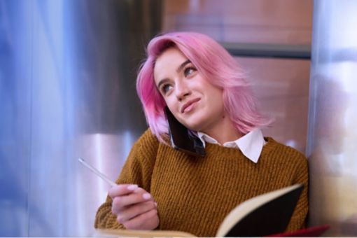 Tertiary student with pink hair on a mobile phone