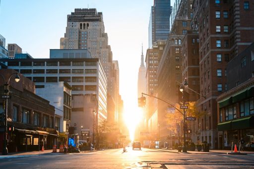 Sunrise on city road between buildings