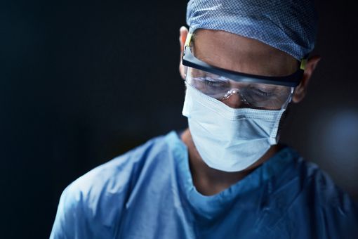 Surgeon wearing surgical mask, cap and glasses