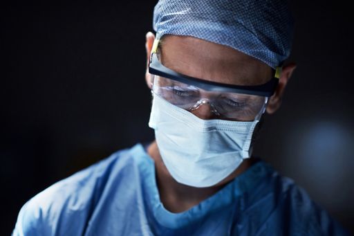Surgeon wearing surgical mask, cap and glasses