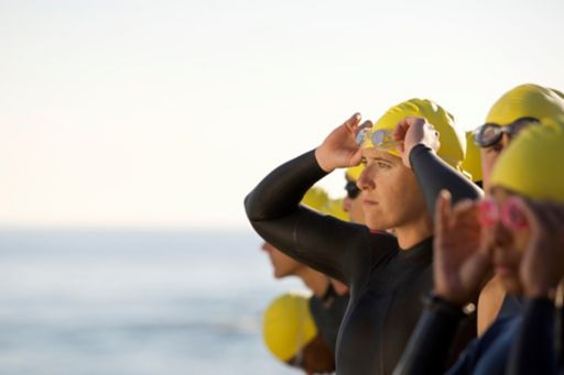 Swimmers wearning black swim suits and yellow cap