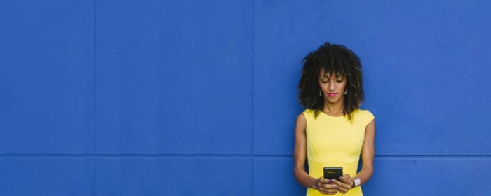 Business woman leaning against a blue background