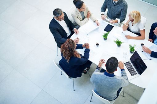 a group of coporate people having a meeting around a whte table
