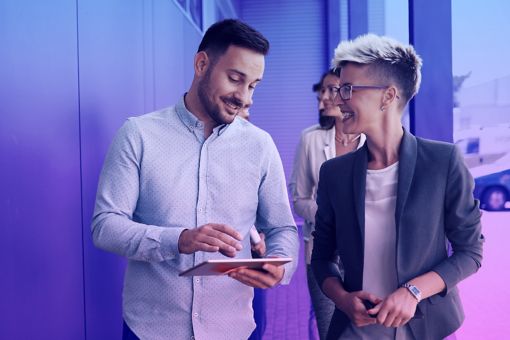 Two men walking with a laptop next to a server room