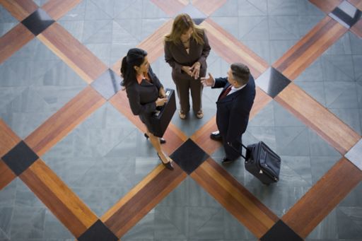 Overhead view of three people standing on grey and orange square floor tiles