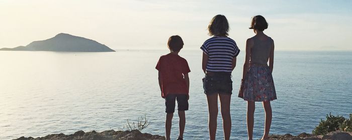 Three children standing near lake