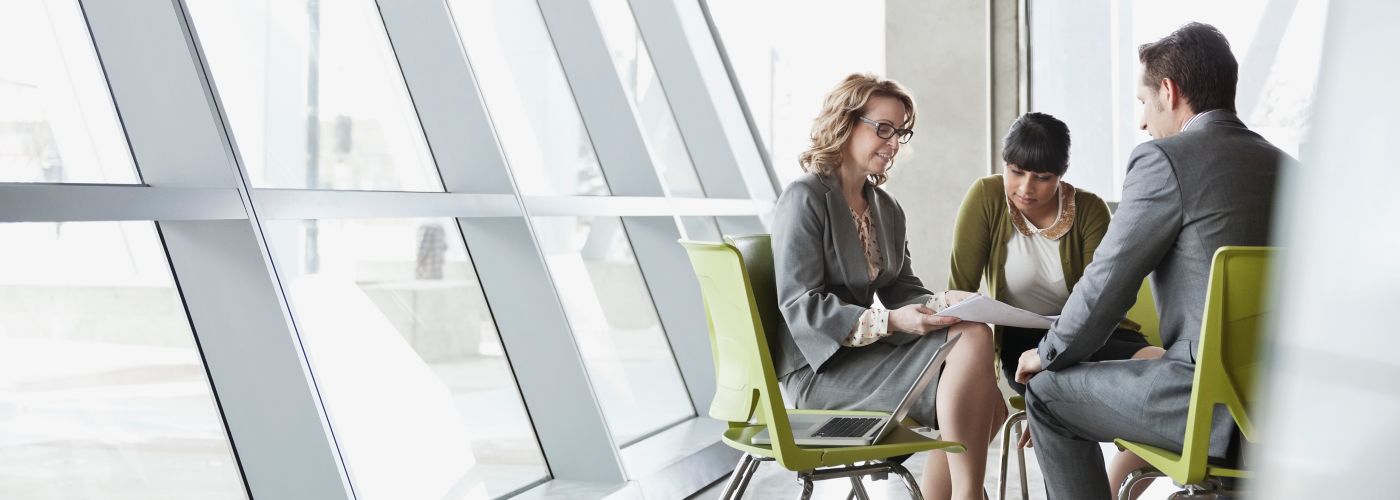 Three people meeting in a glass atrium