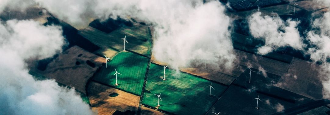 Top view of green field of windmills with clouds 