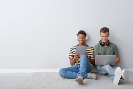 Two boys listening music and looking at laptop and tablet