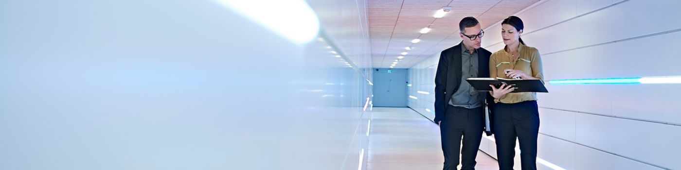 Two business people discussing a file in a corridor