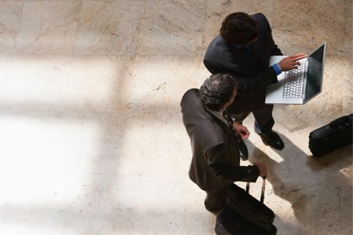 Two businessmen looking at laptop in lobby