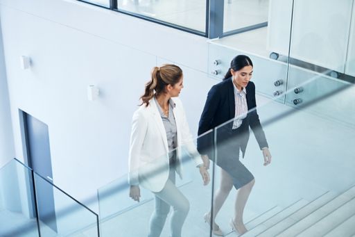 Shot of two businesswomen having a discussion while walking in a modern office
