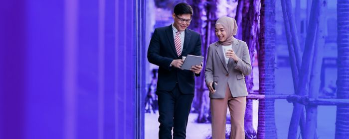 two colleagues walking in the street looking at tablet