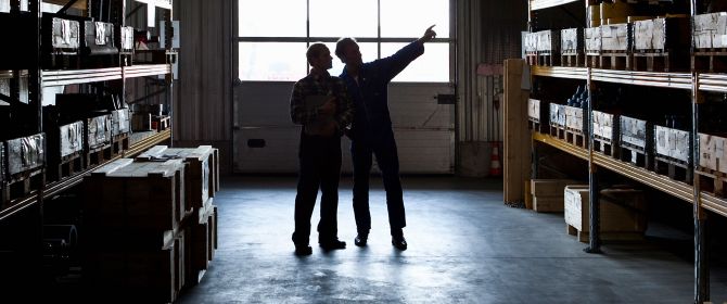 Two workers in a metal parts warehouse