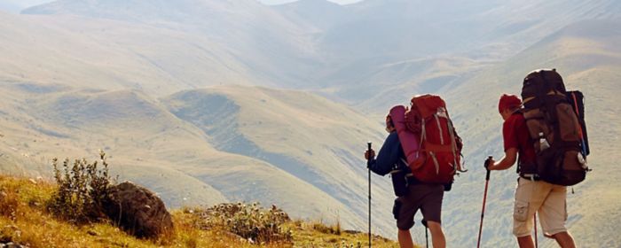 Two men trekking on mountain with heavy backpacks