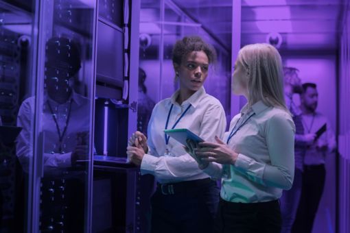 Two women looking at each other whilst in a server room