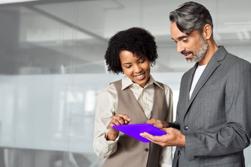 Two people in an office looking down interacting with a purple tablet