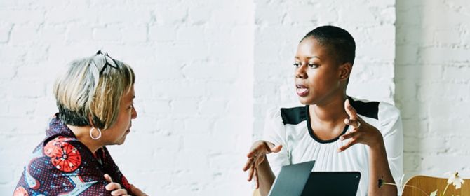 Two women talking while working