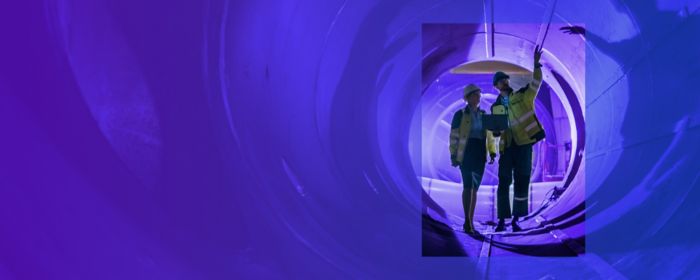 two workers viewing inside of pipe