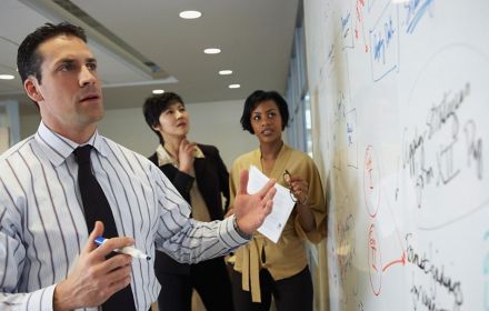Three people looking at whiteboard