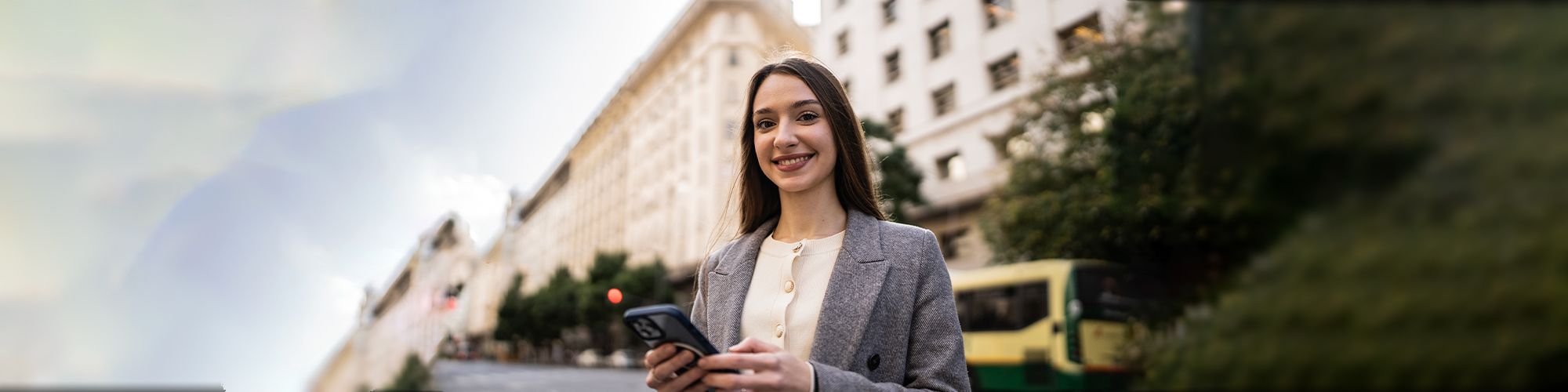 Mujer utilizando un dispositivo inteligente en mano frente a un instituto