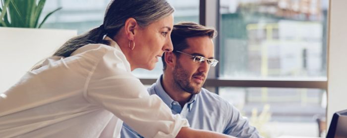 Femme et homme montrant un écran d'ordi au bureau