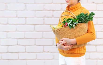 A woman carrying fruits and vegetables in a bag