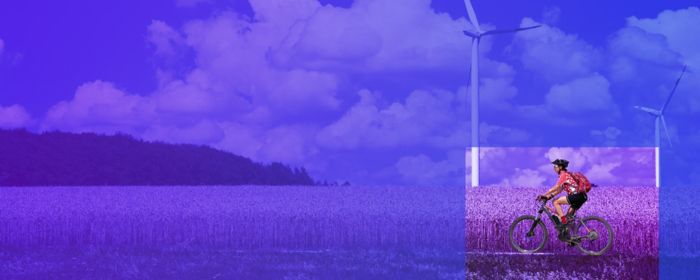 woman cycling in front of field and wind turbines