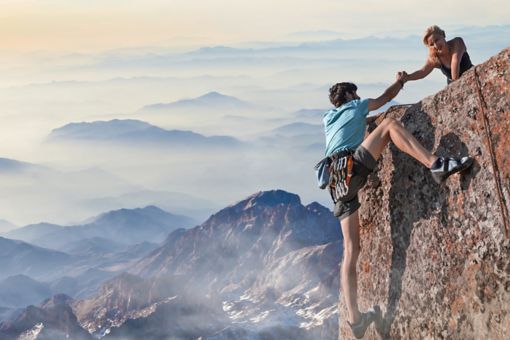 Woman helping man climbing mountain