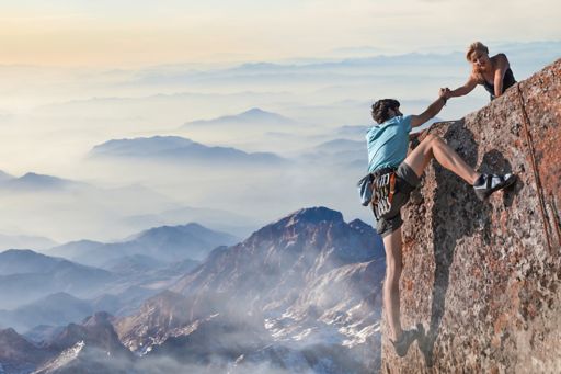 Woman helping man climbing mountain