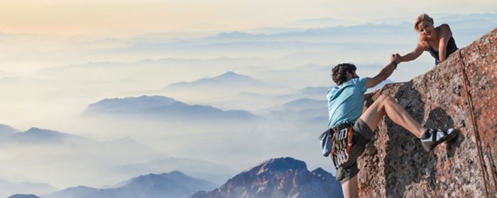  woman helping a man in climbing a mountain