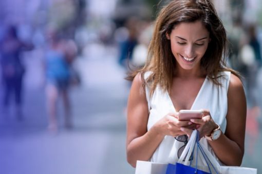 Woman holding shopping bags and texting on her phone
