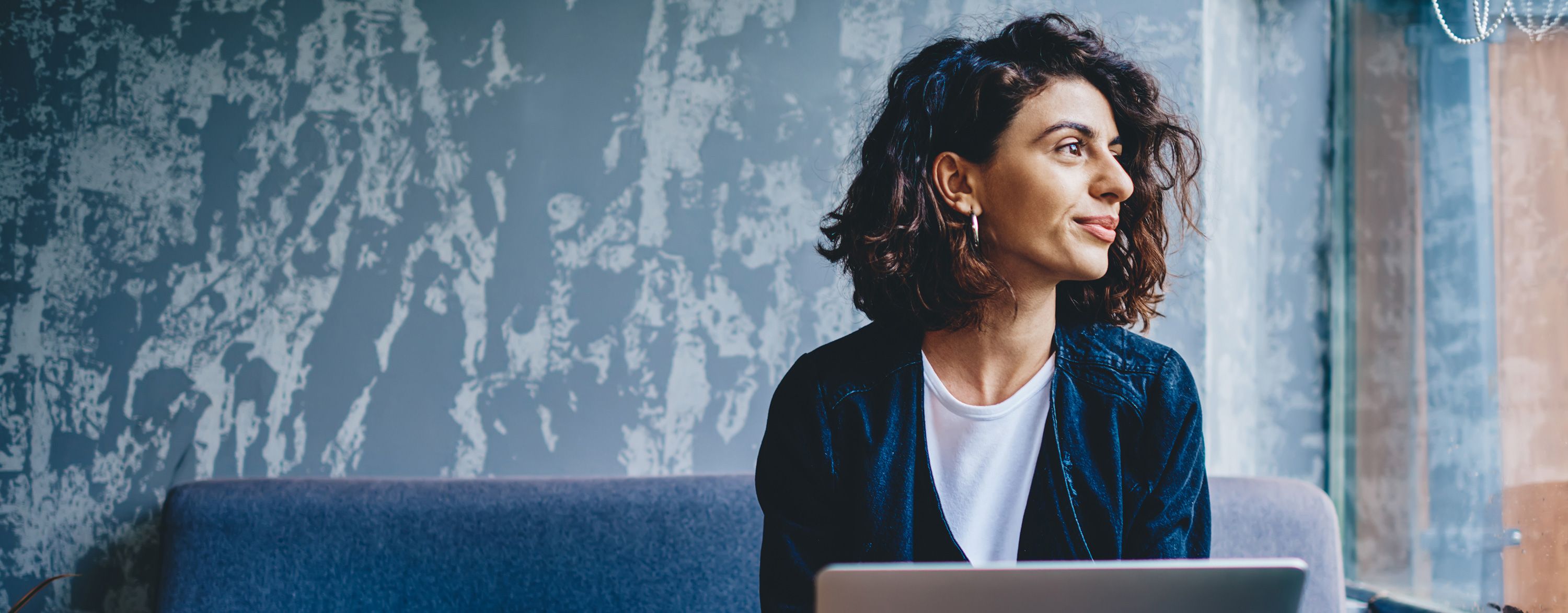 Business woman using laptop looking out window