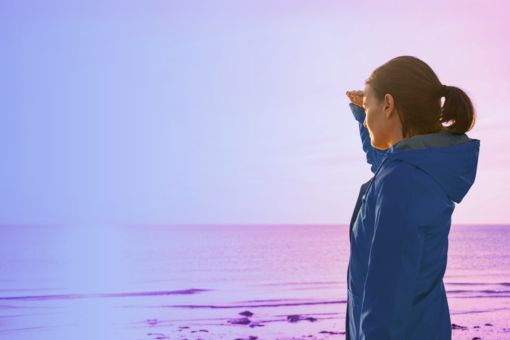 woman on beach looking towards sun