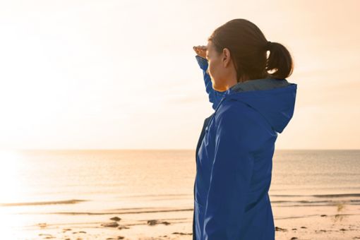 woman on beach looking towards sun