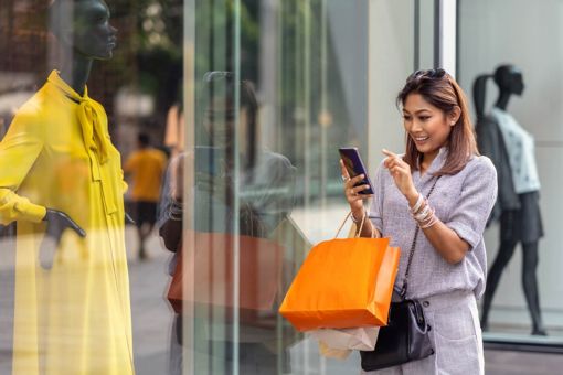 Woman online shopping outside retail store