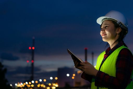 Woman on a construction site with city lights at night